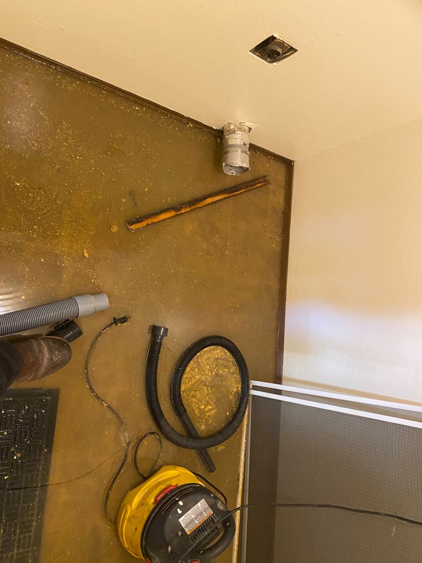 Bathroom floor covered in sewage residue with extraction hose and vacuum