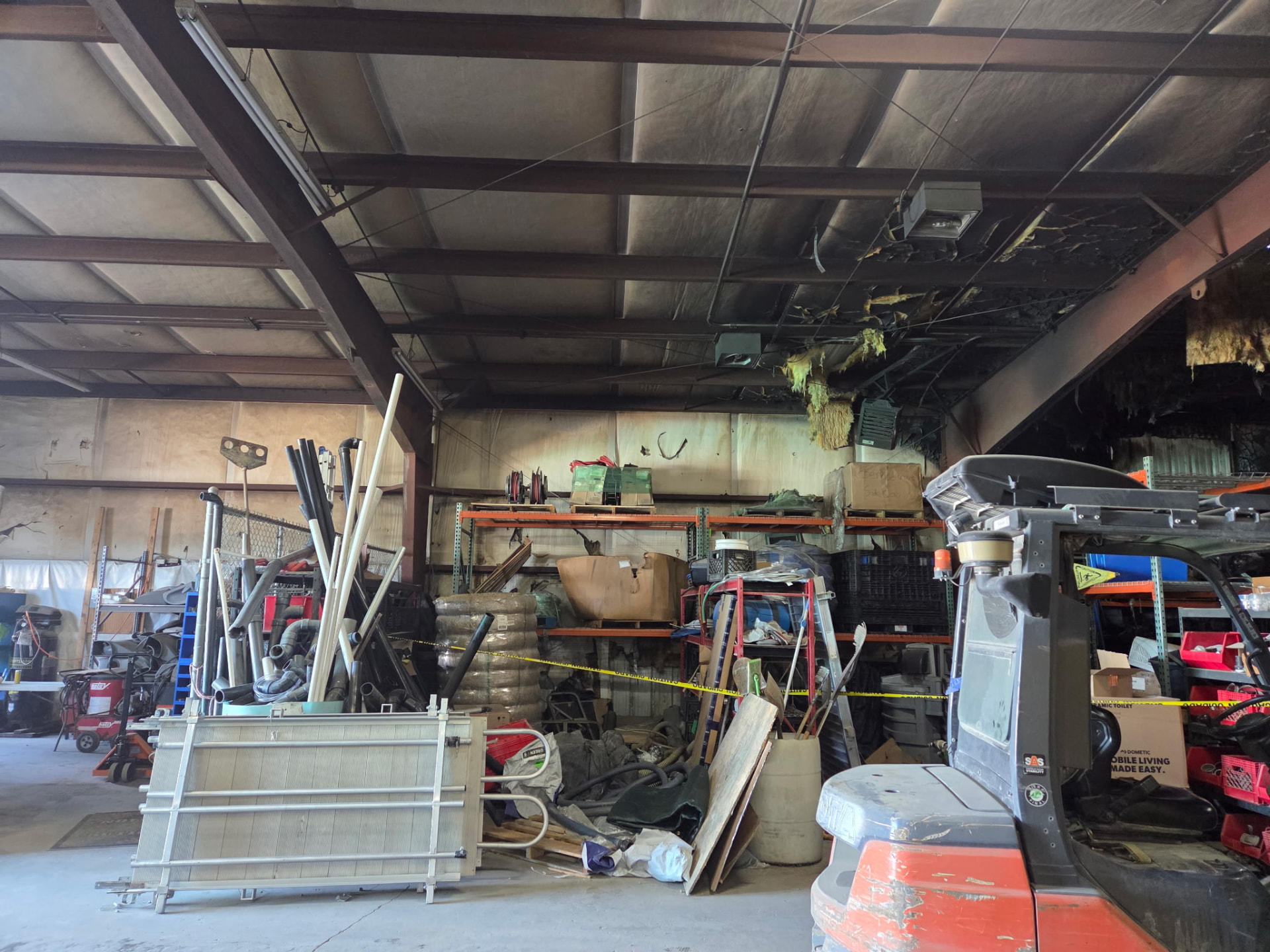 Fire damage to the roof structure and burned insulation inside a commercial warehouse