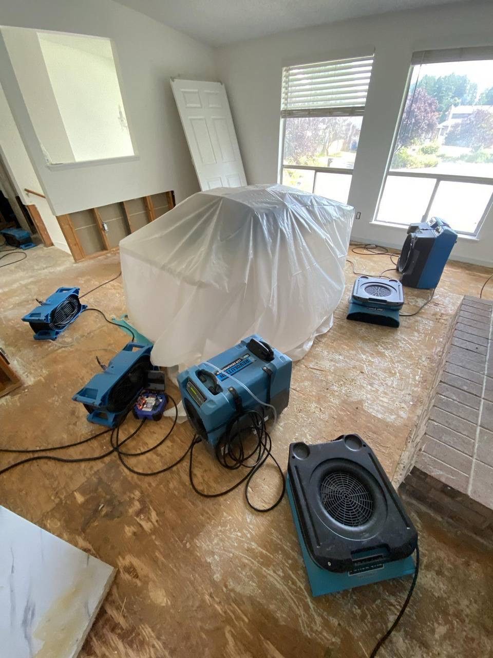Dehumidifiers and air movers drying a water-damaged living room