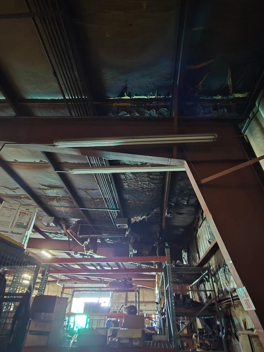 Charred ceiling panels and smoke-blackened beams inside a fire-damaged commercial building