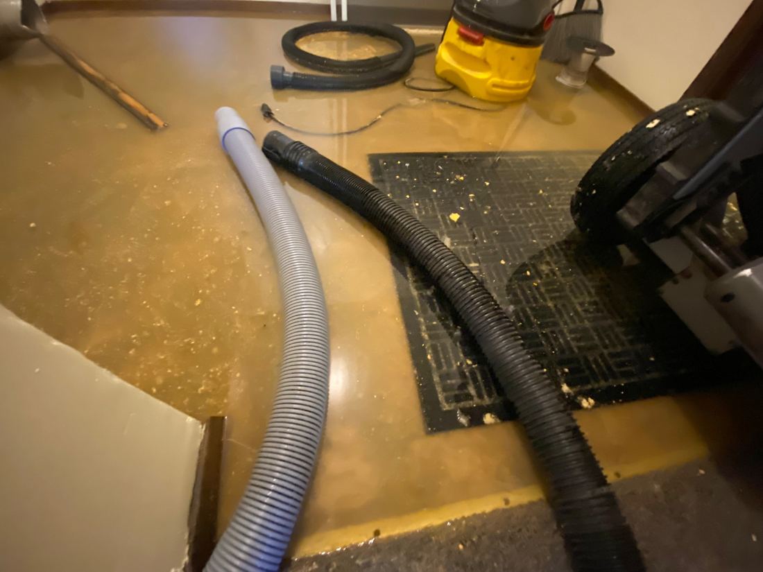 Extraction hoses and wet vacuum on a sewage-contaminated bathroom floor in Seattle
