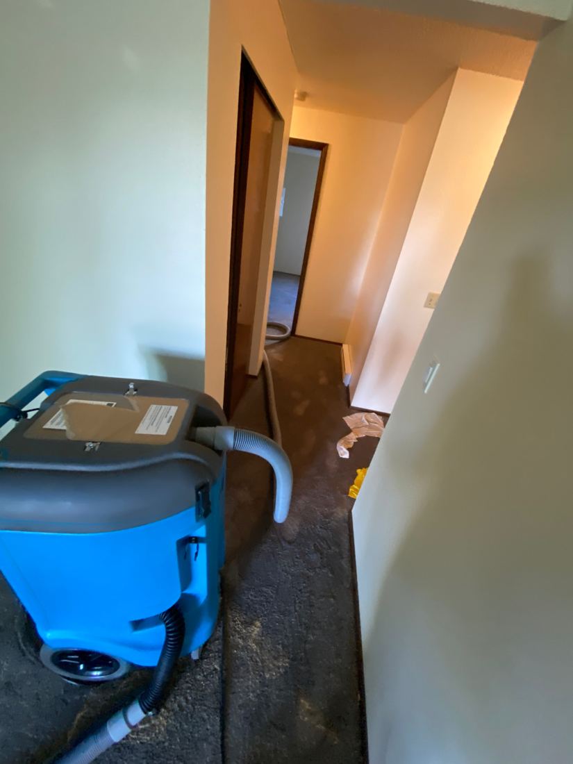 Portable carpet extractor in an apartment hallway affected by a sewage backup